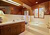 Master private bathroom with a deep soaking bath tub, located to the right of the bedroom.,