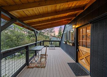 Large deck with outdoor seating and entryway to home is covered.