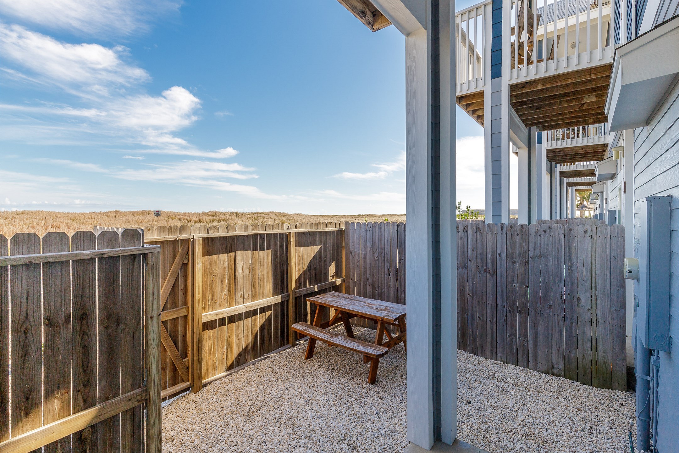 Fenced in private patio with a picnic table and a gate for easy access to the beach