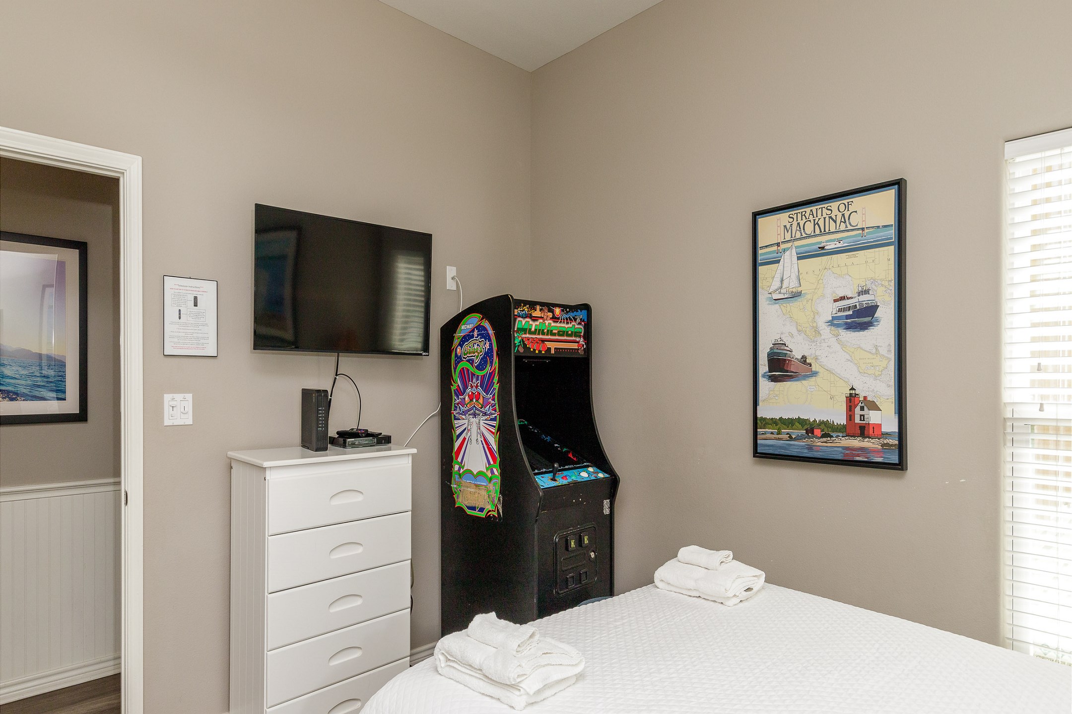 Second bedroom with queen size bed, twin bunk beds, and an arcade game 