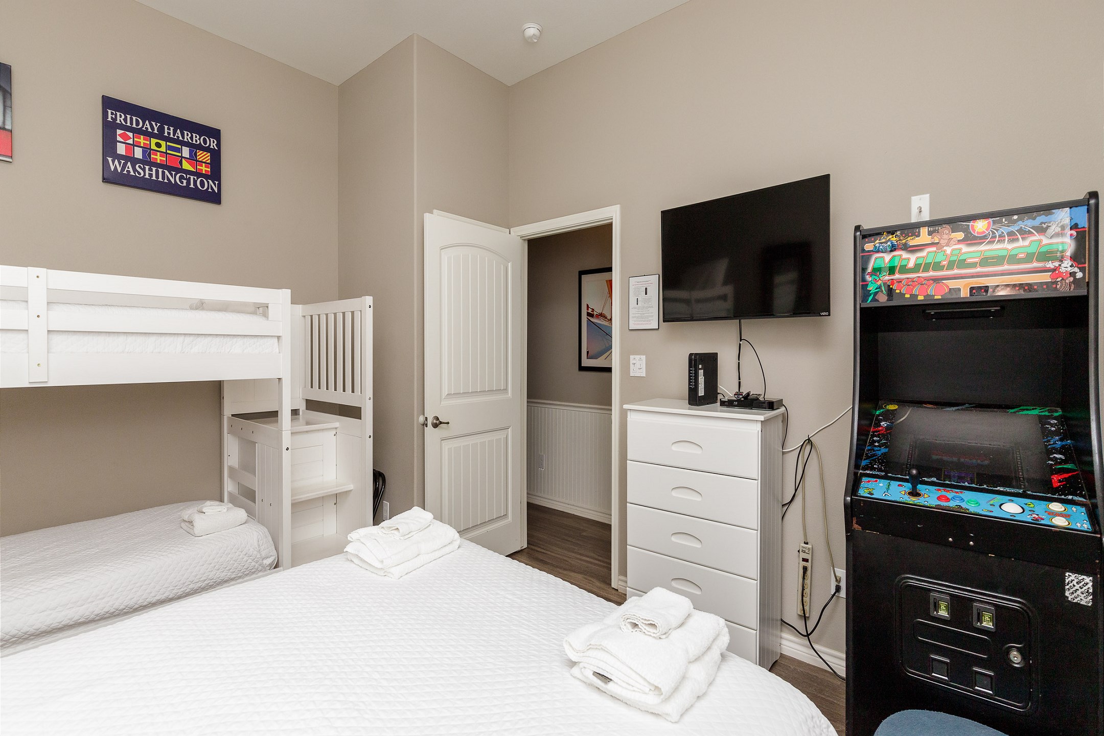 Second bedroom with queen size bed, twin bunk beds, and an arcade game 
