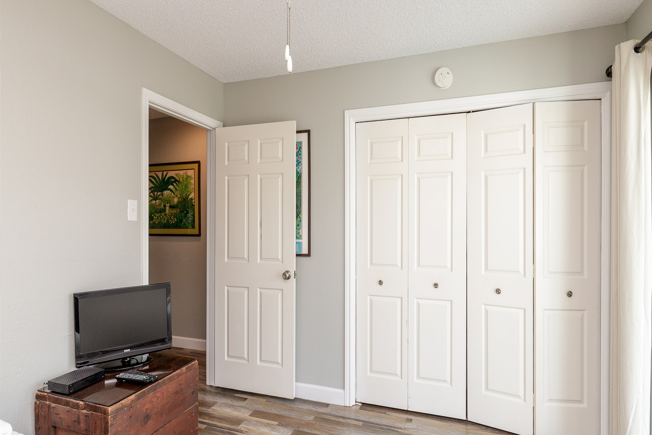 Guest bedroom with two twin size beds, flat screen TV, and private balcony overlooking the pool 
