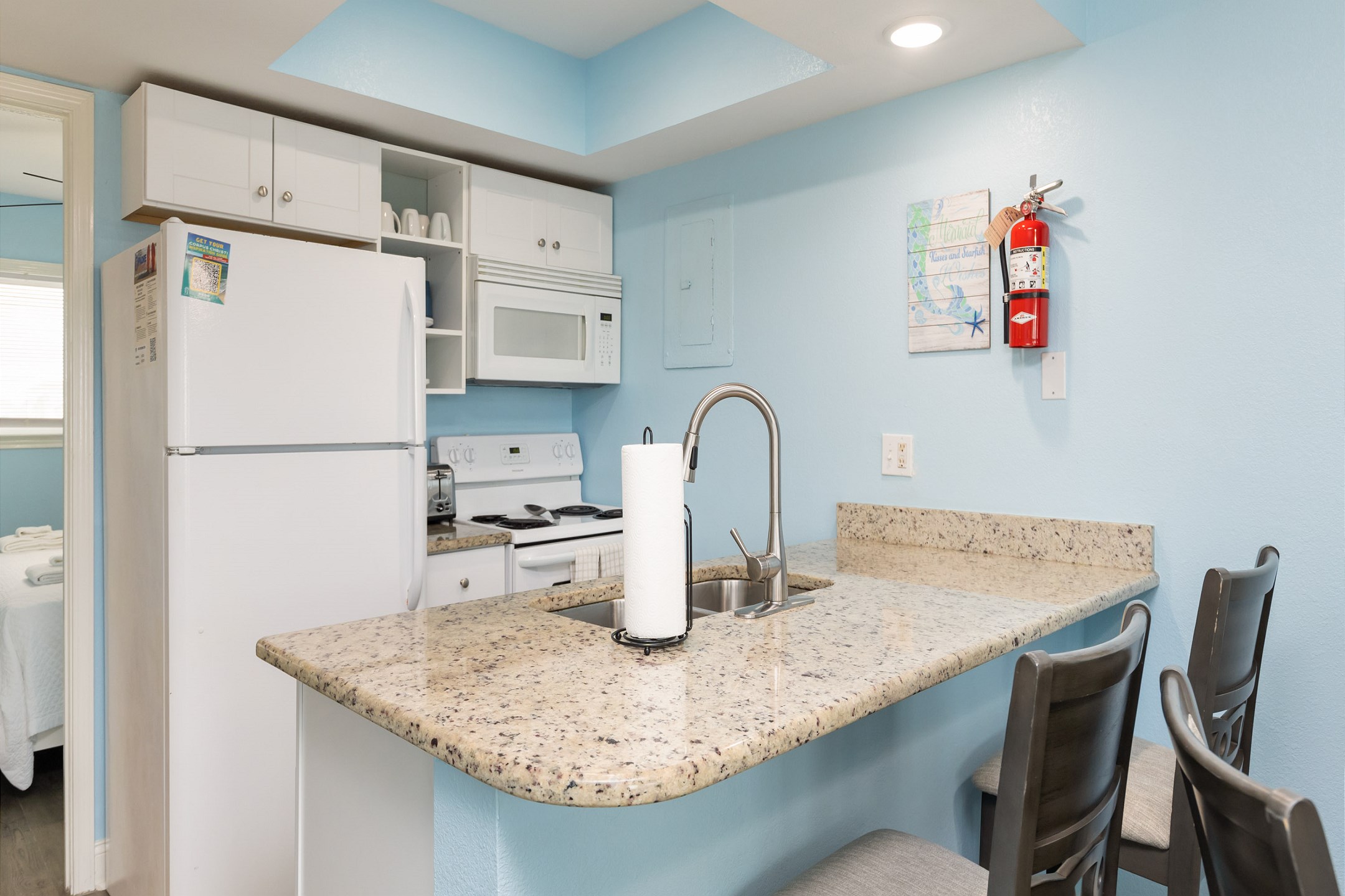 Well stocked kitchen with barstools and full cup coffee maker 