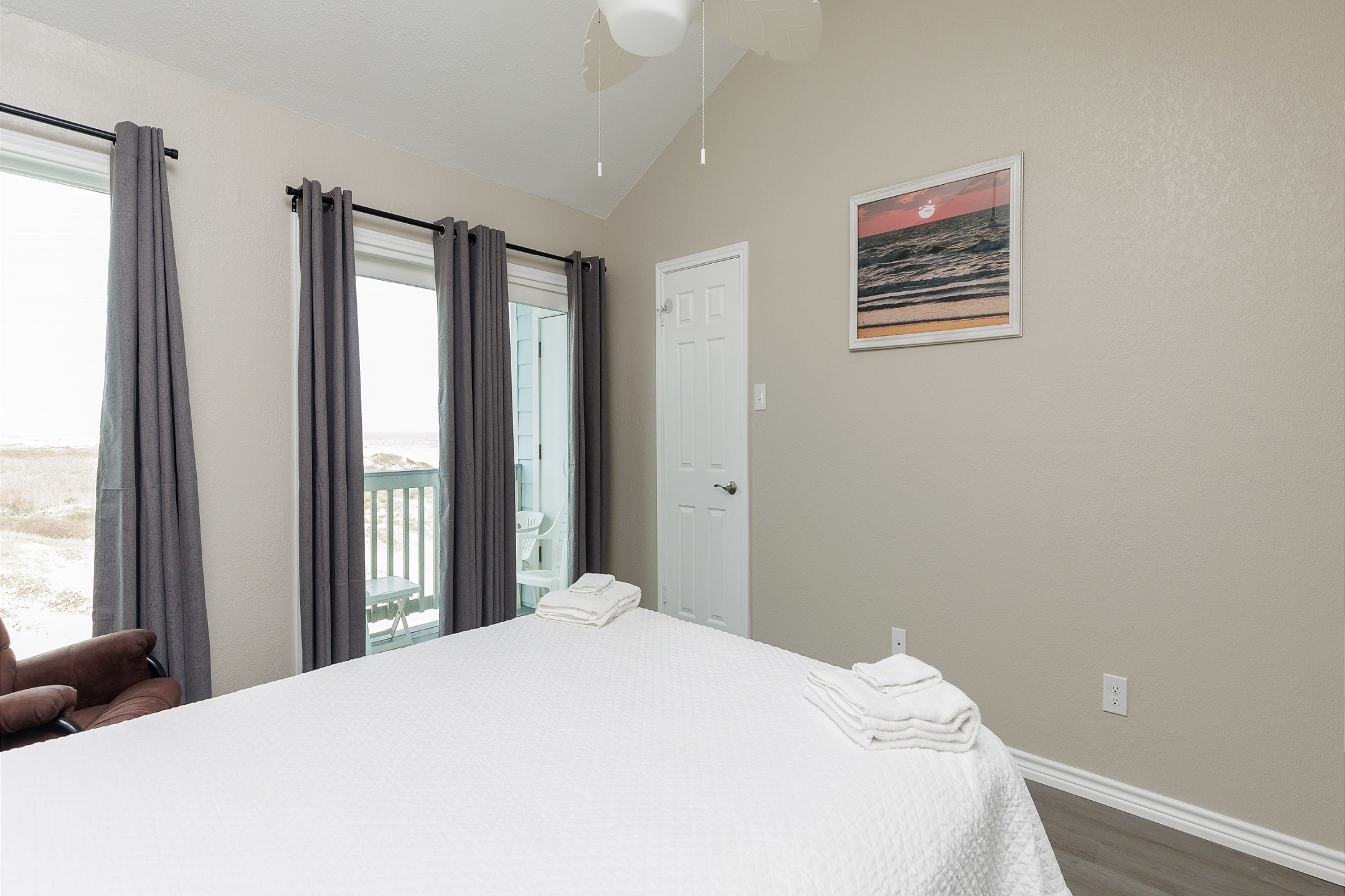Master bedroom on the second floor, featuring a queen-size bed, private balcony with a beach view, and a private bathroom