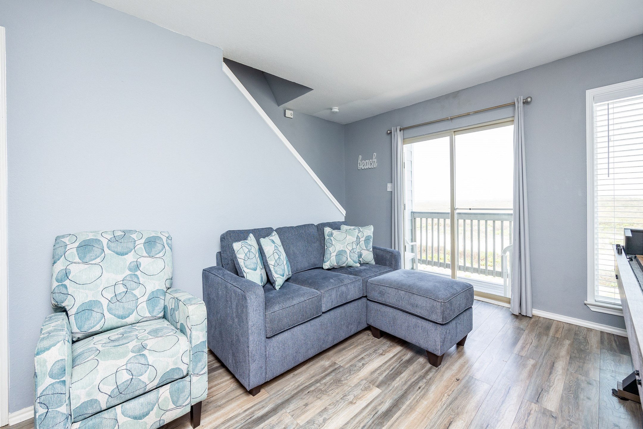 Bright living area with a sofa sleeper and access to private balcony with a beach view 