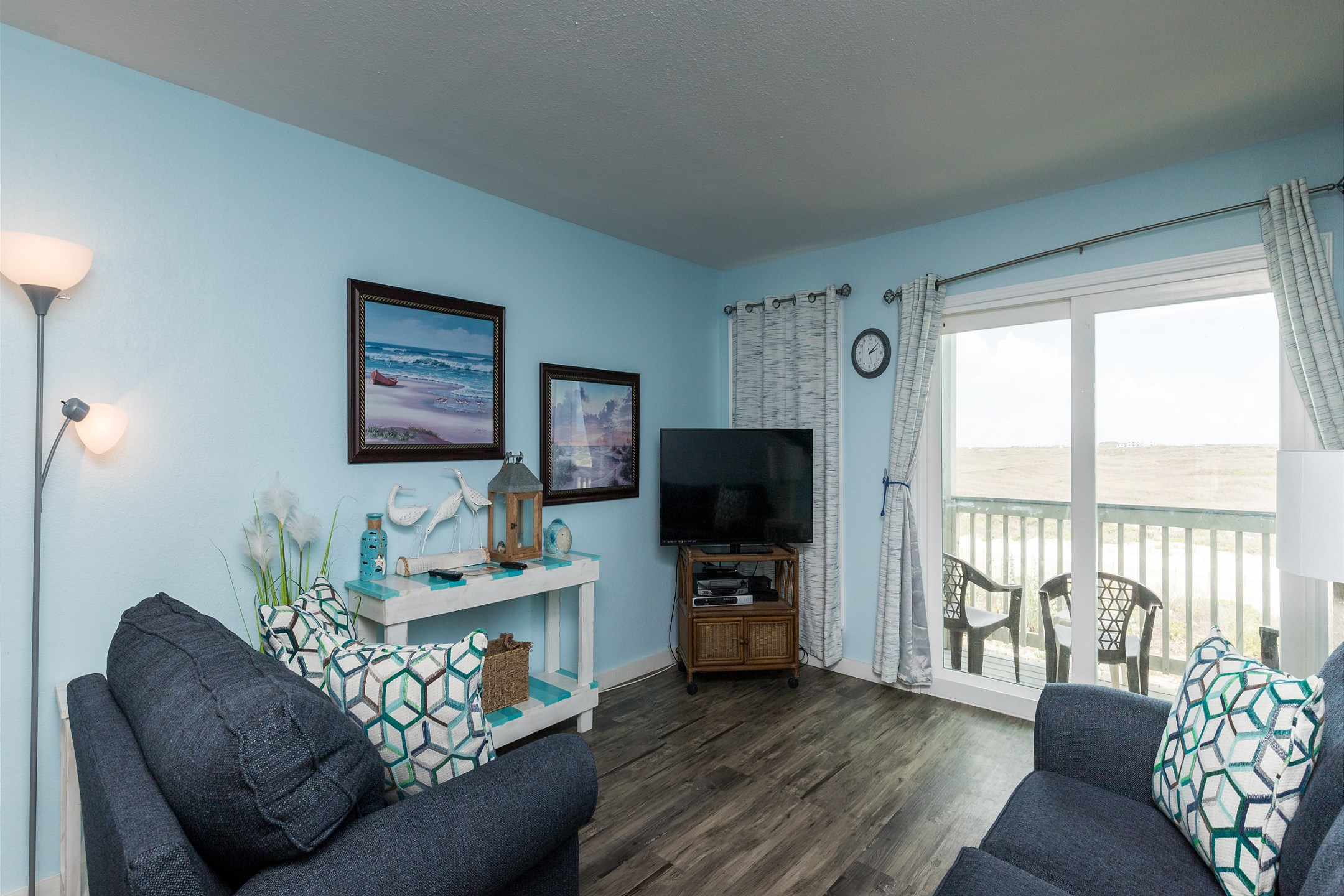 Updated living space with new couches and a private balcony with chairs 