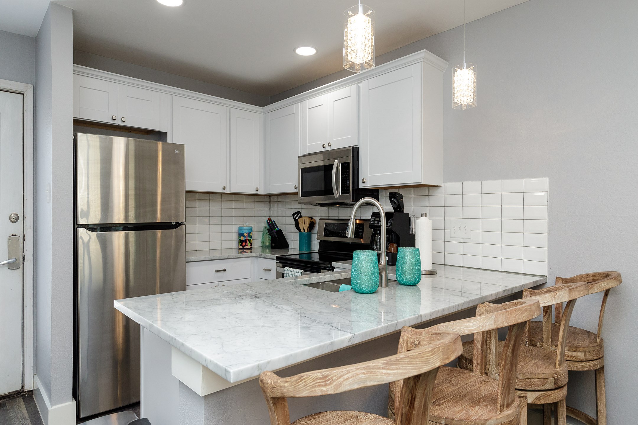 Fully equipped kitchen with stainless steel appliances and breakfast bar that seats three