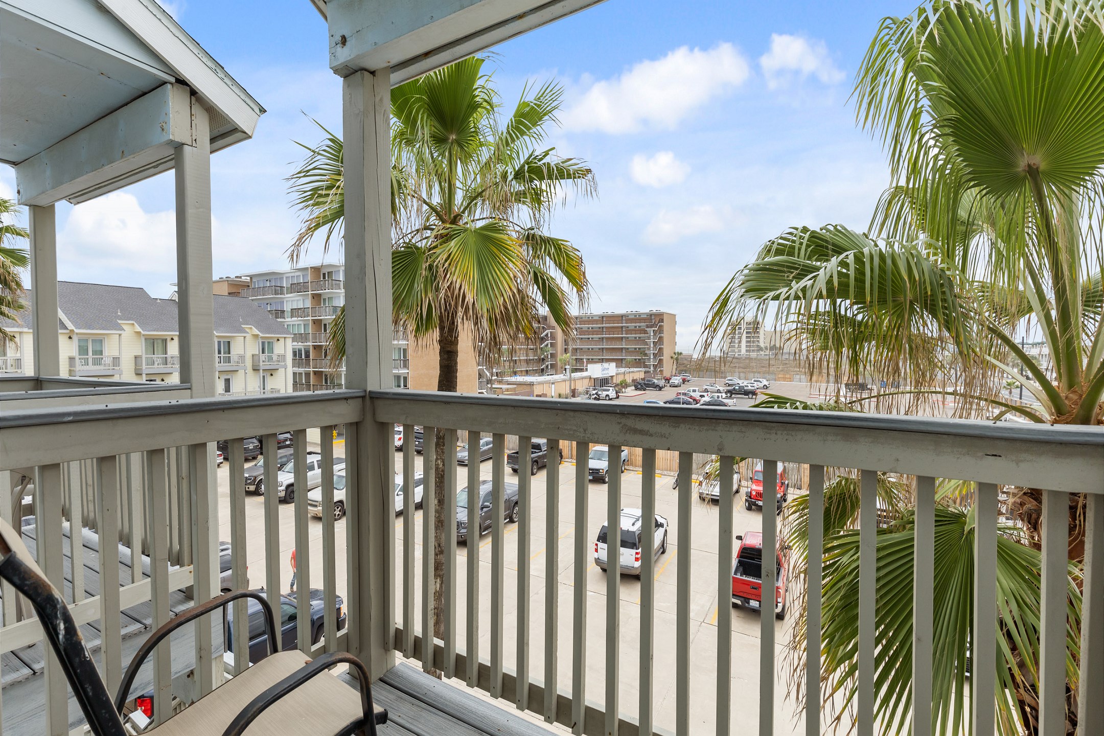 Private balcony off the second bedroom with chairs and parking lot view 