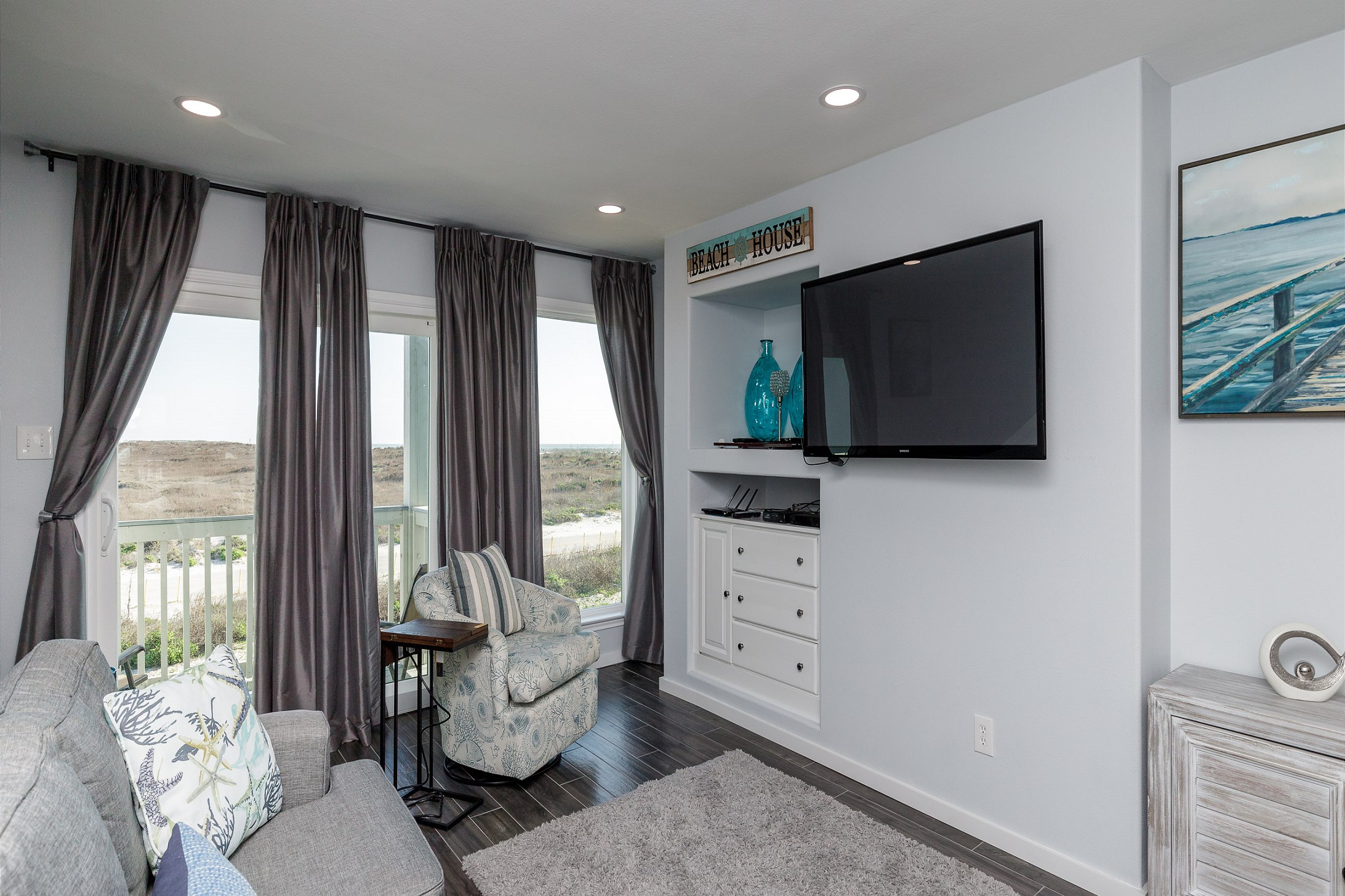 Inviting living space with queen size sleeper sofa, flat screen TV and partial beach view from the private balcony