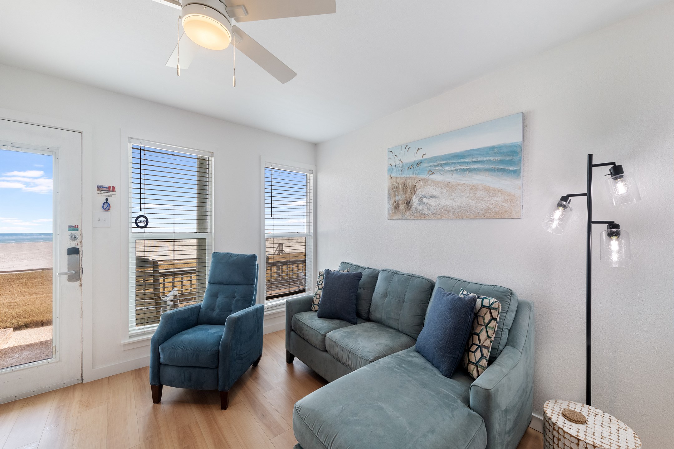 Living area with new furniture, flooring throughout and a beautiful view of the beach from the large windows