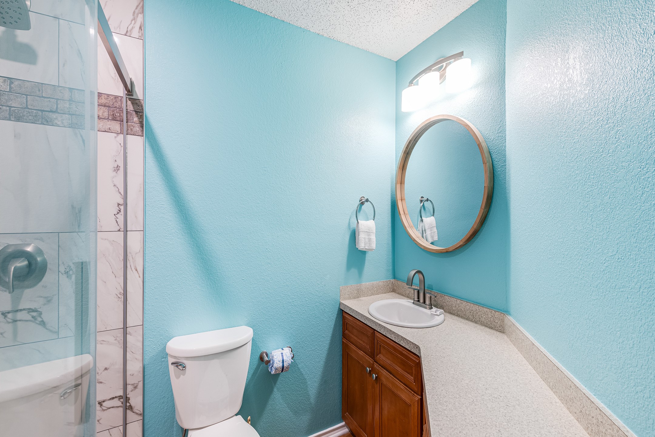 Bathroom featuring toilet, sink, and walk-in shower 
