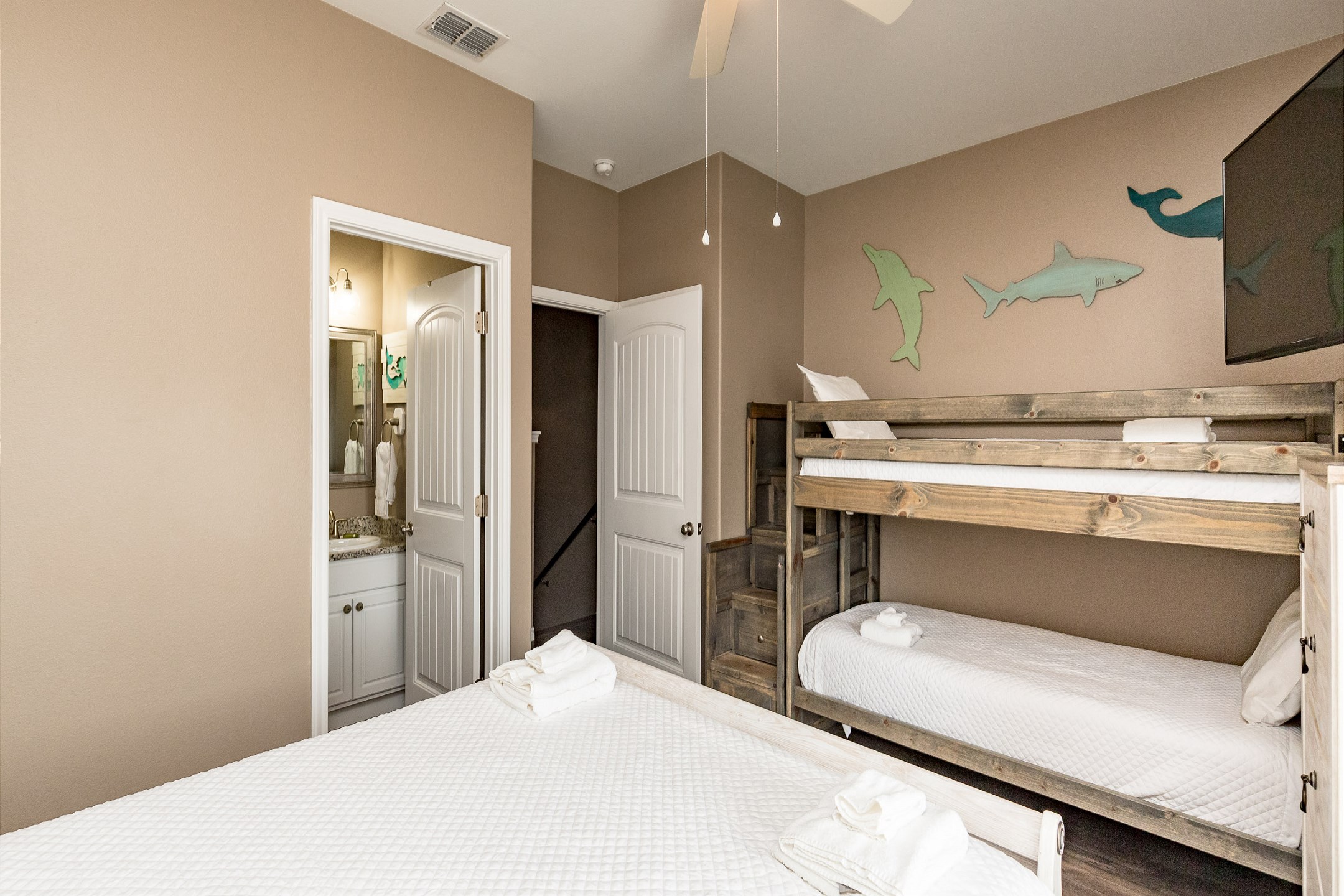 Second bedroom on the second floor with queen size bed, twin size bunk beds, private balcony, private bathroom, and flat screen TV