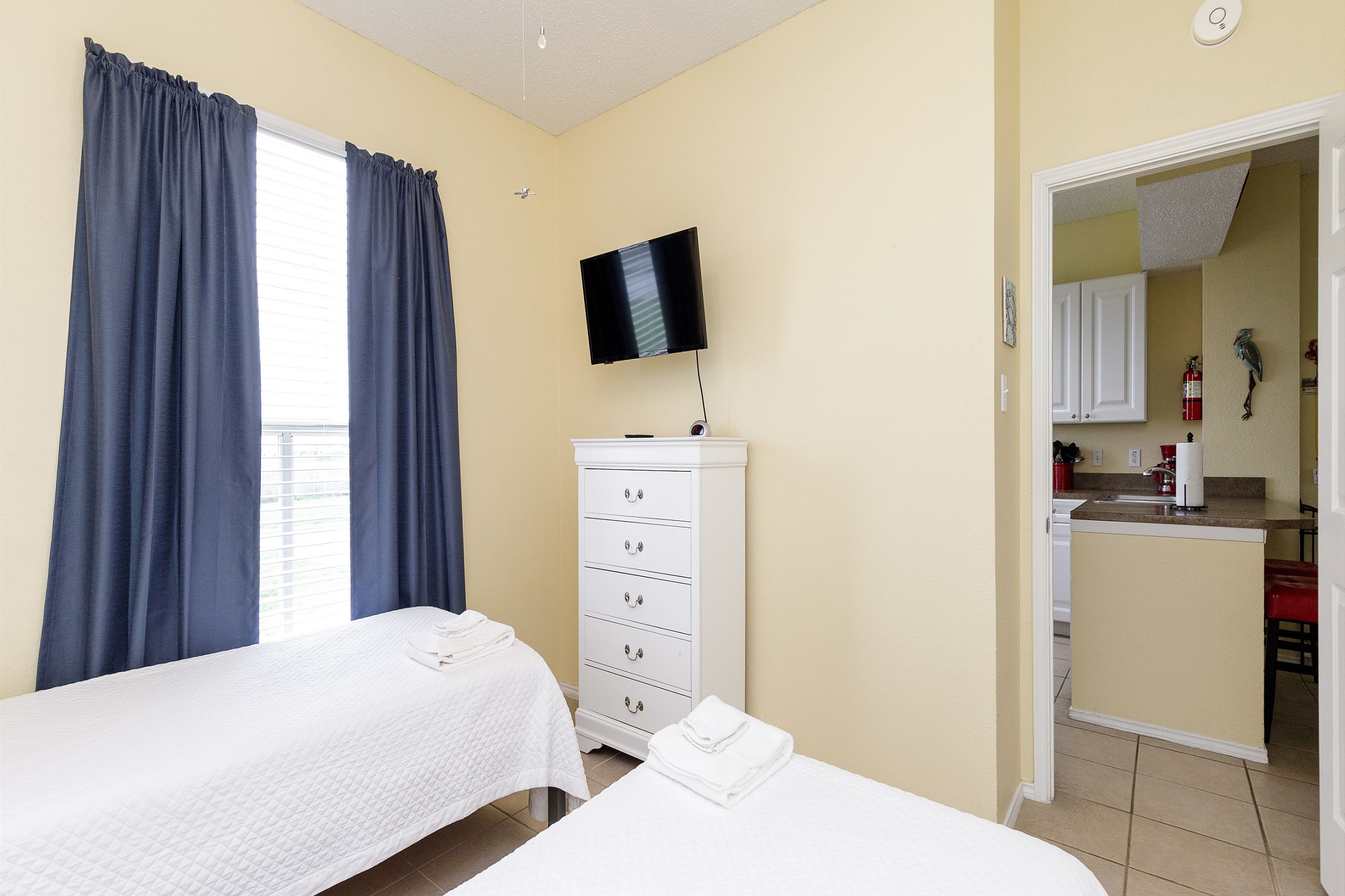 Second bedroom with two twin size beds and mounted TV