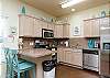 Fully equipped kitchen with stainless steel appliances and breakfast bar that seats two