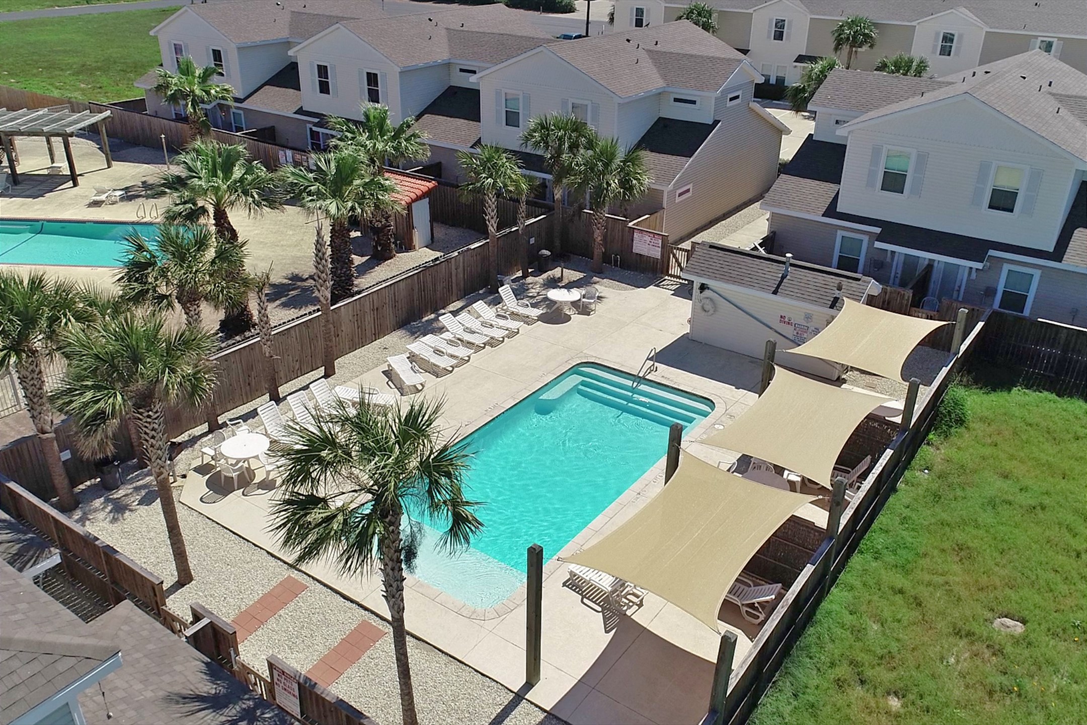 Leeway Bay community pool with loungers, shades and tropical palm trees all around - Time to soak in the sun for your vacation