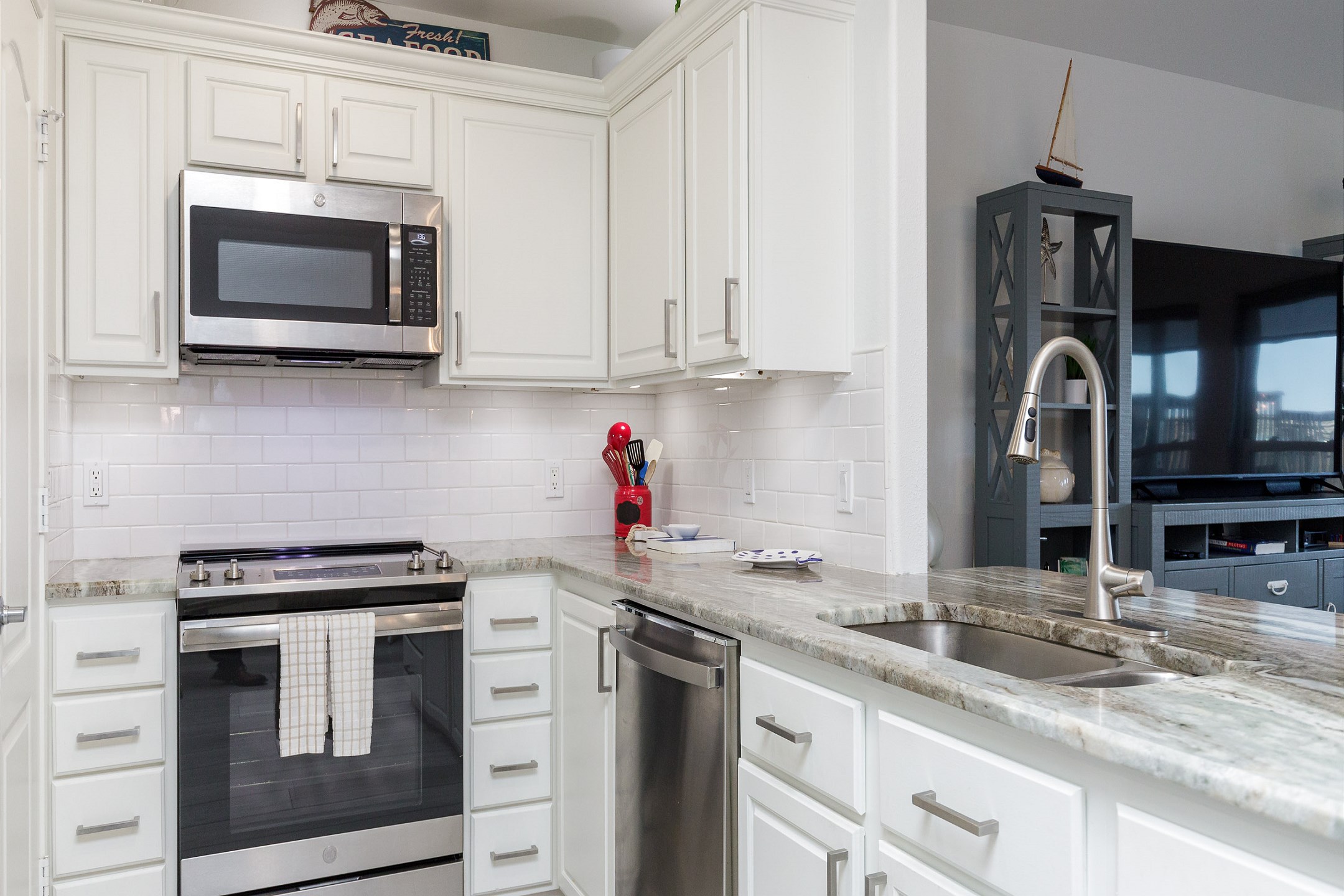 Fully equipped kitchen with updated appliances, tall white cabinets and beautiful counter tops 