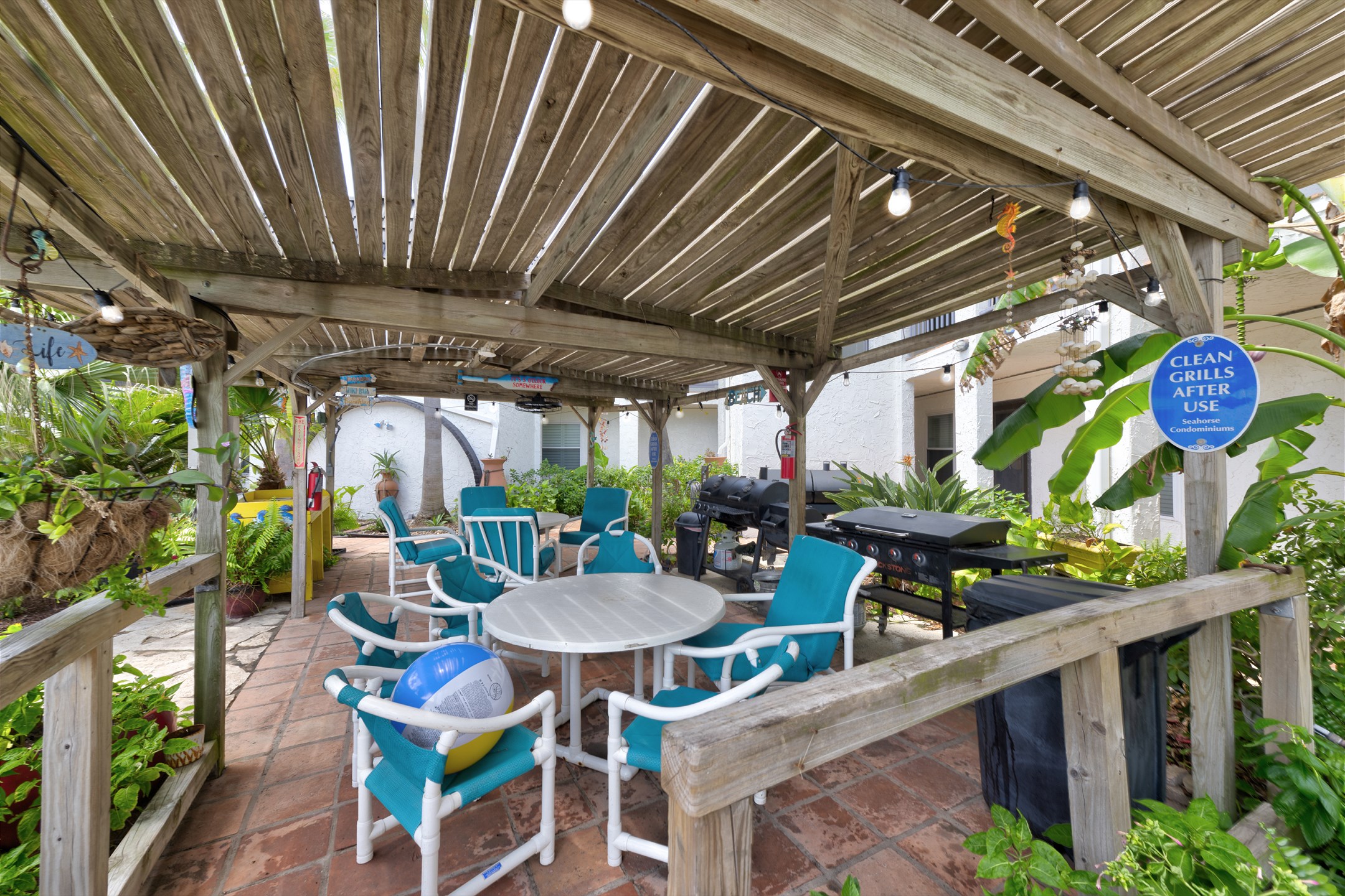 Inviting community pool space with comfortable chairs and multiple grills for guest use