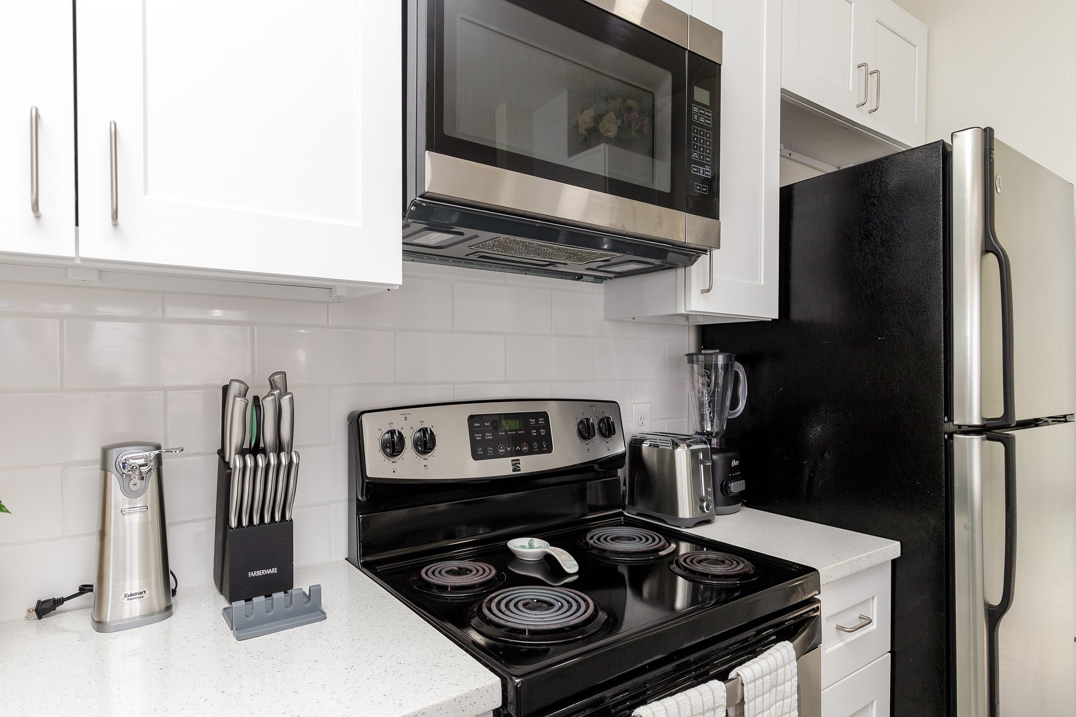 Fully equipped kitchen with stainless steel appliances, coffee maker, toaster, cookware, dinnerware, and other kitchen essentials provided