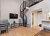 Living space with dining table and flat screen TV, stairs leading to the loft space