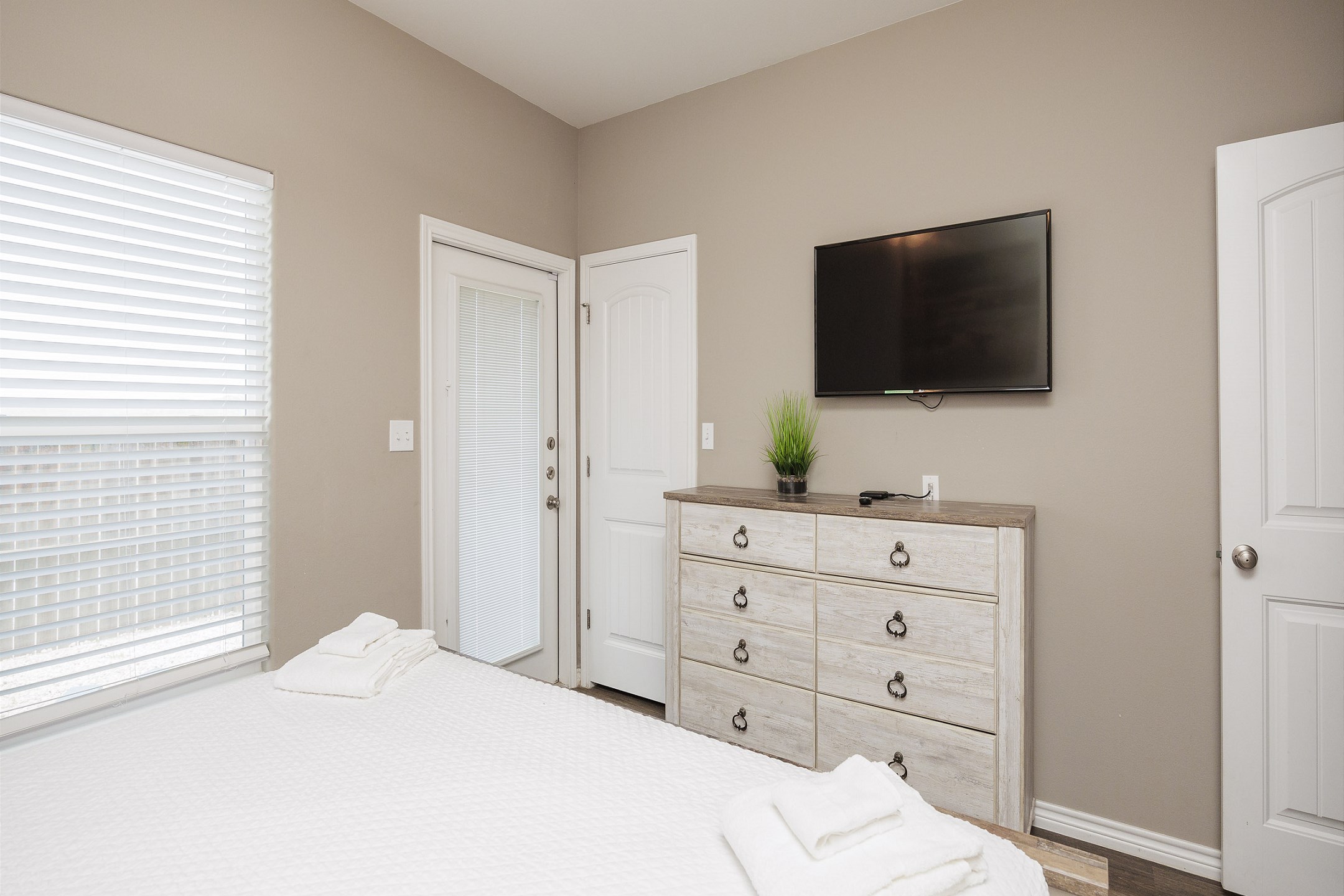 Primary bedroom on the first floor with a king bed, ensuite bathroom, TV, and direct access to the private patio.
