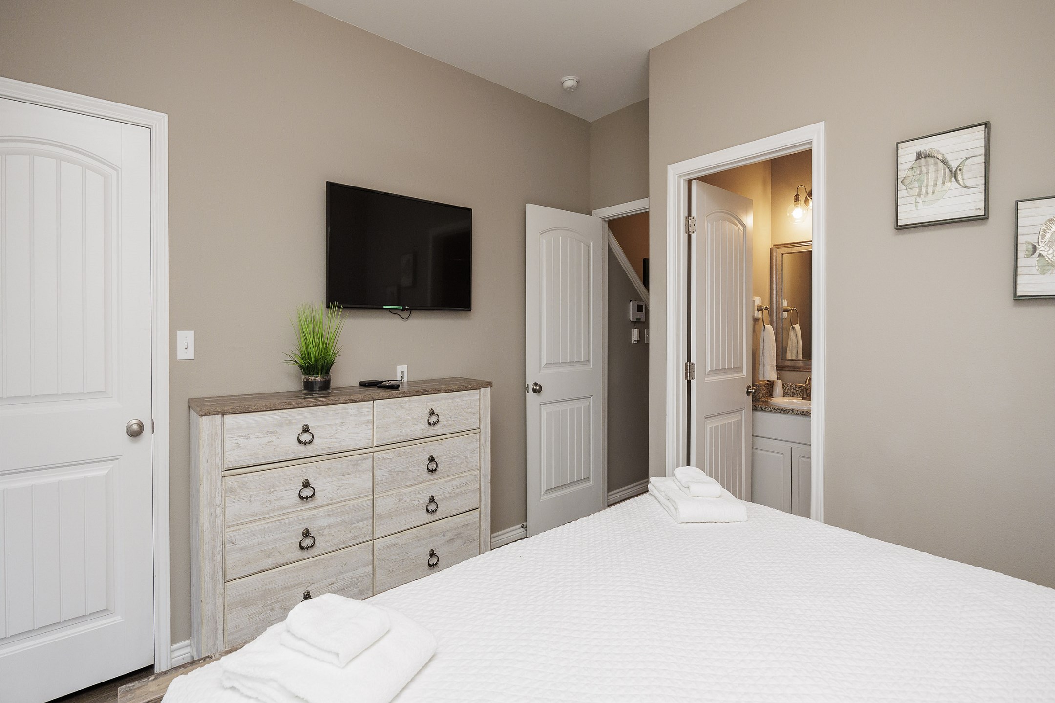 Primary bedroom on the first floor with a king bed, private bathroom, TV, and direct access to the private patio.