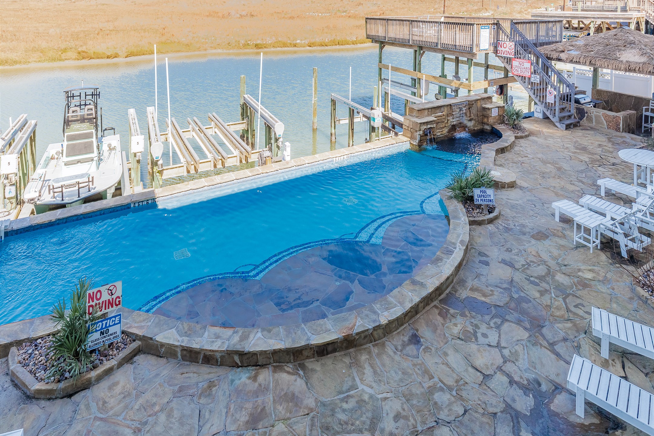 Large infinity pool with waterfalls, lounge chairs and canal views to enjoy 