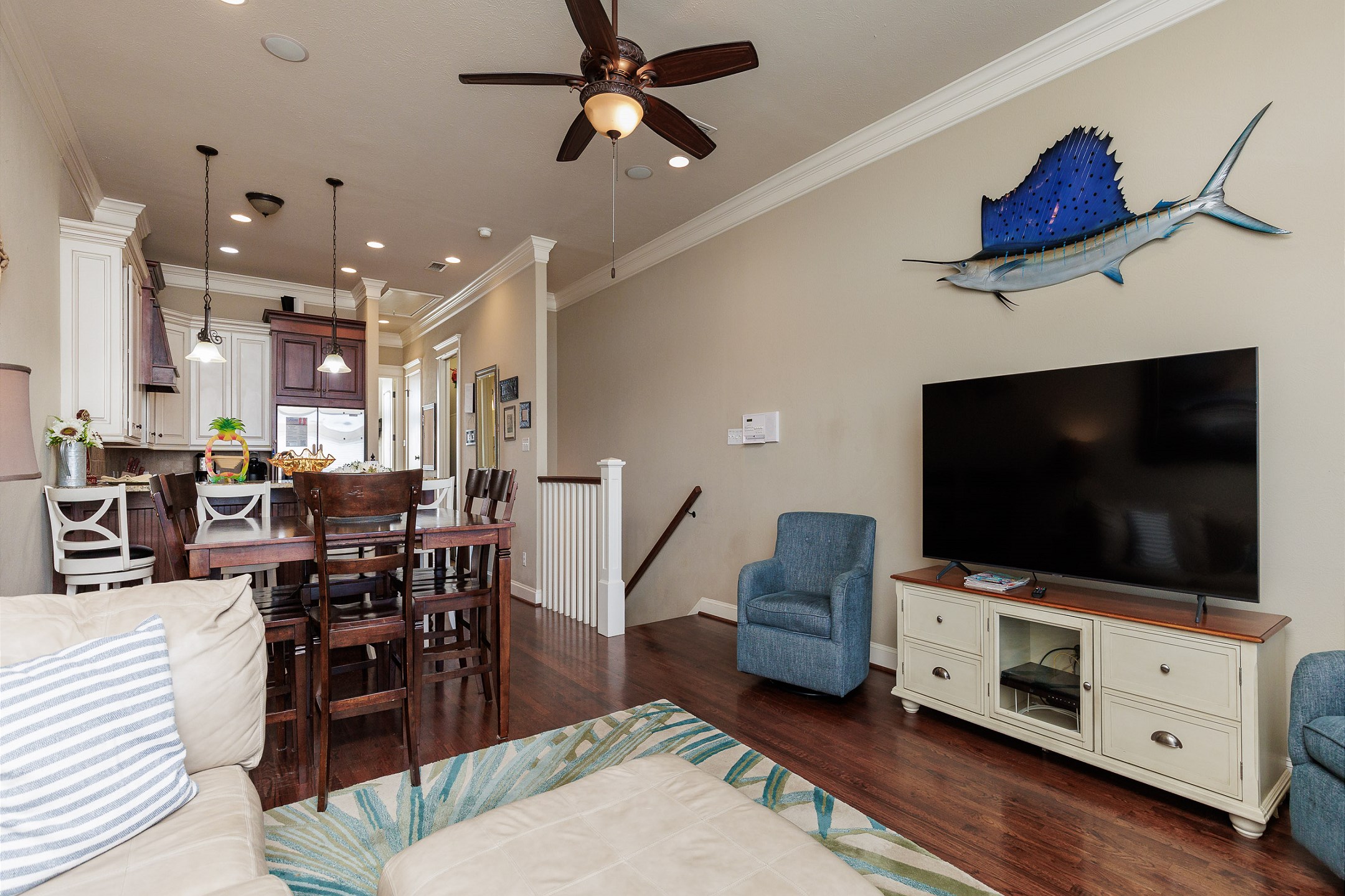 Open concept living, dining, and kitchen area on the third floor. Blue accent chairs have been removed. 