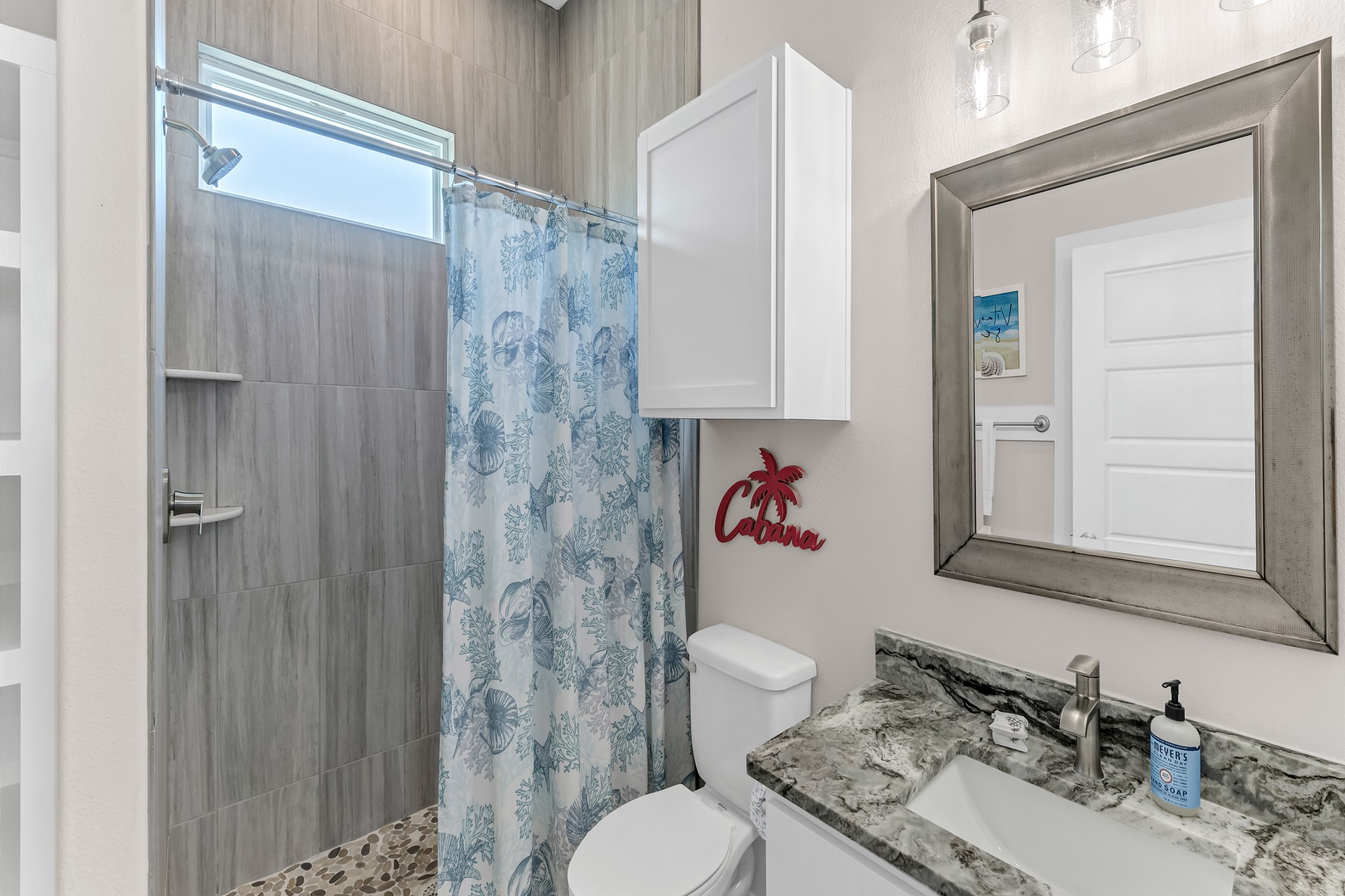 Guest bathroom with single sink, toilet, and walk in shower 