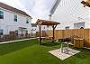 Picnic table with pergola cover, offers shade while the kids play on the turf grass and dinner gets cooked on the grill.