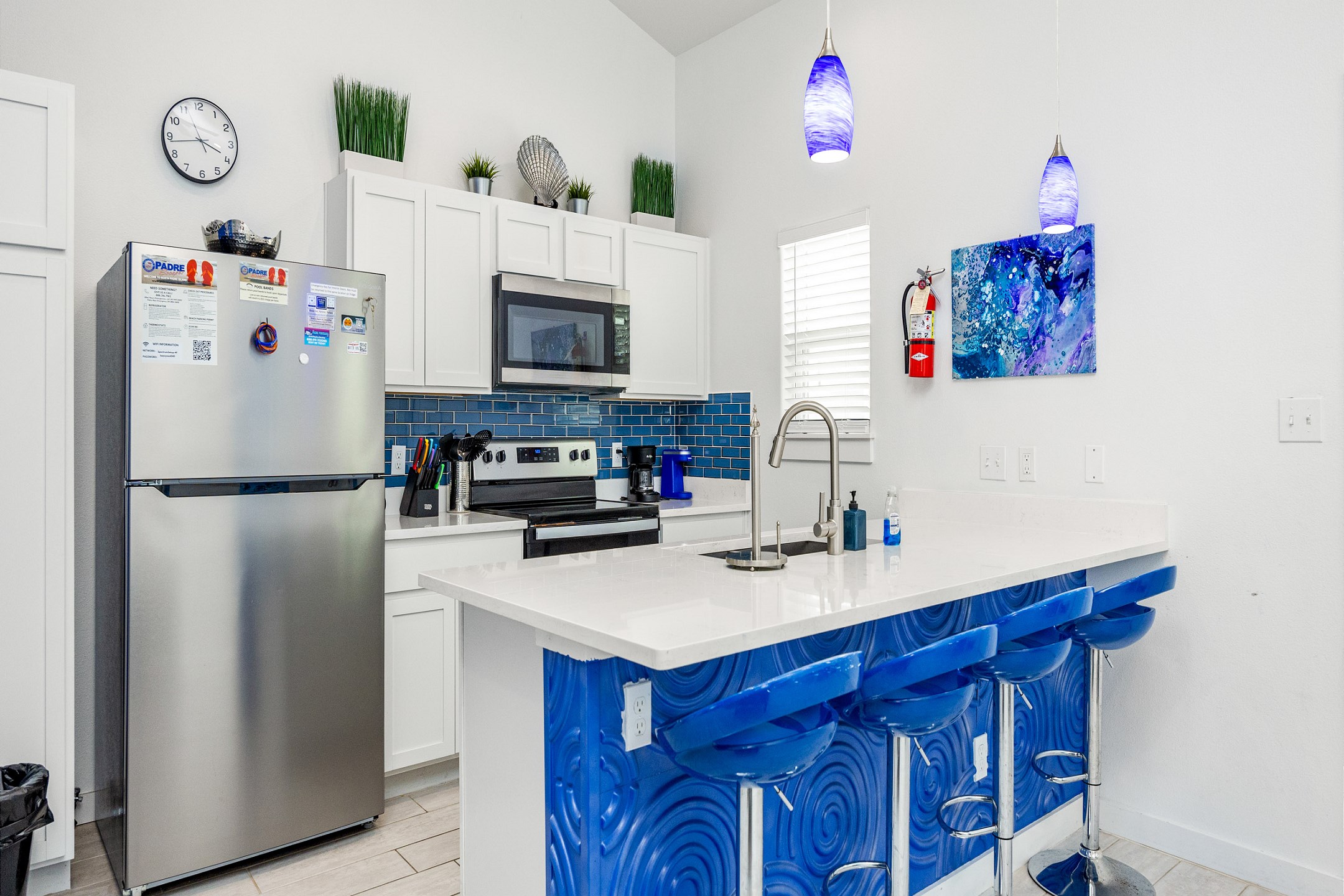 Fully equipped kitchen with barstools, modern decor, and coffee maker