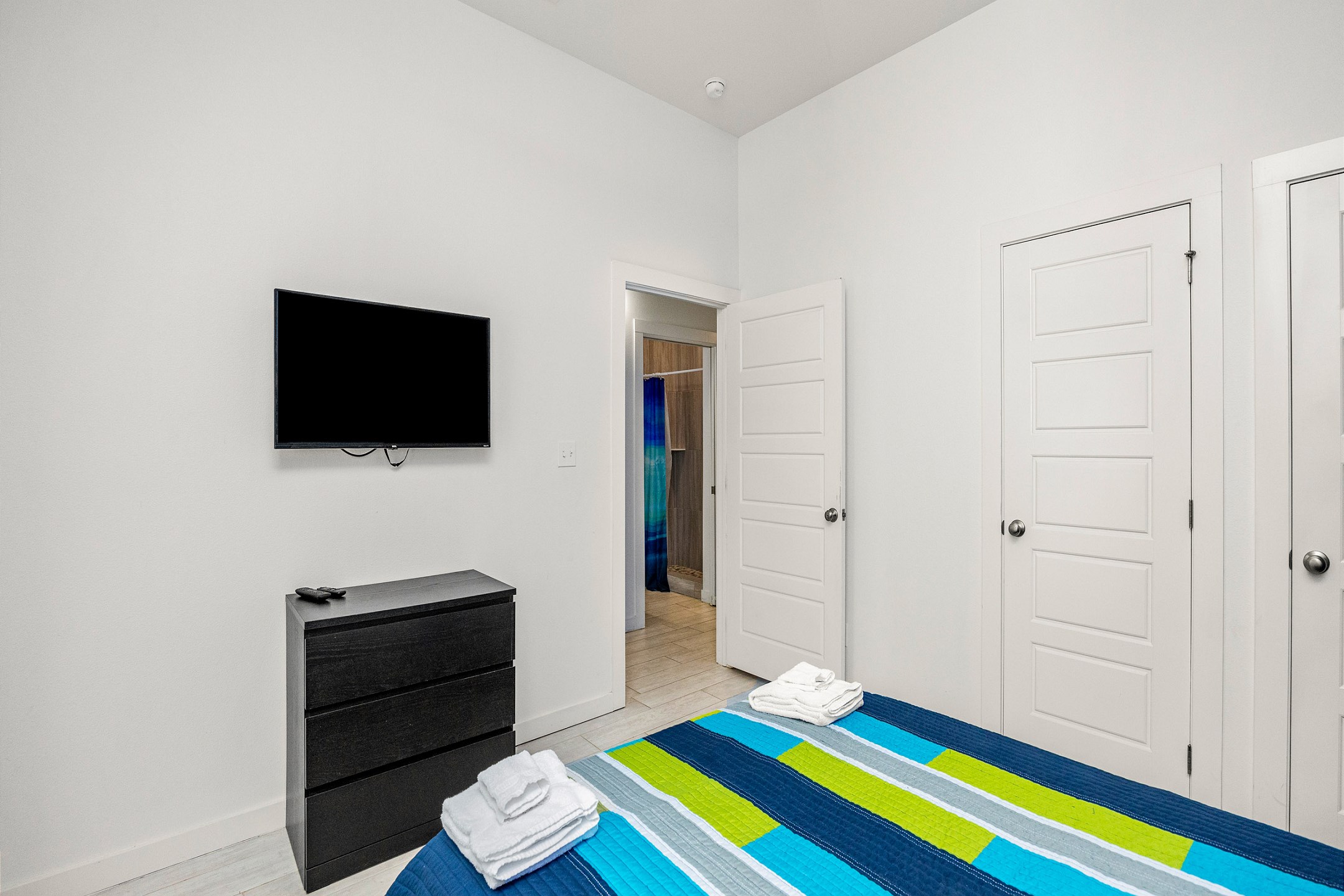 Master bedroom with queen size bed, flat screen TV, and back patio access