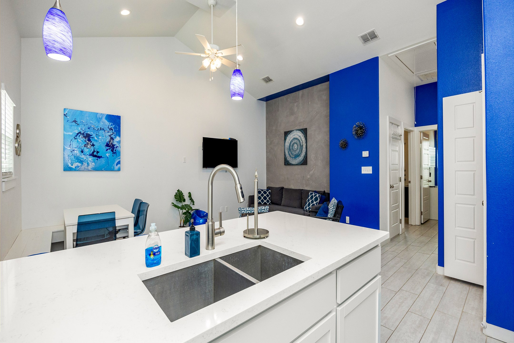 Kitchen area with bright white marble counter top that over looks the living and dining area 