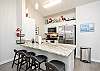 Bright open concept kitchen area with barstools and coffee maker 