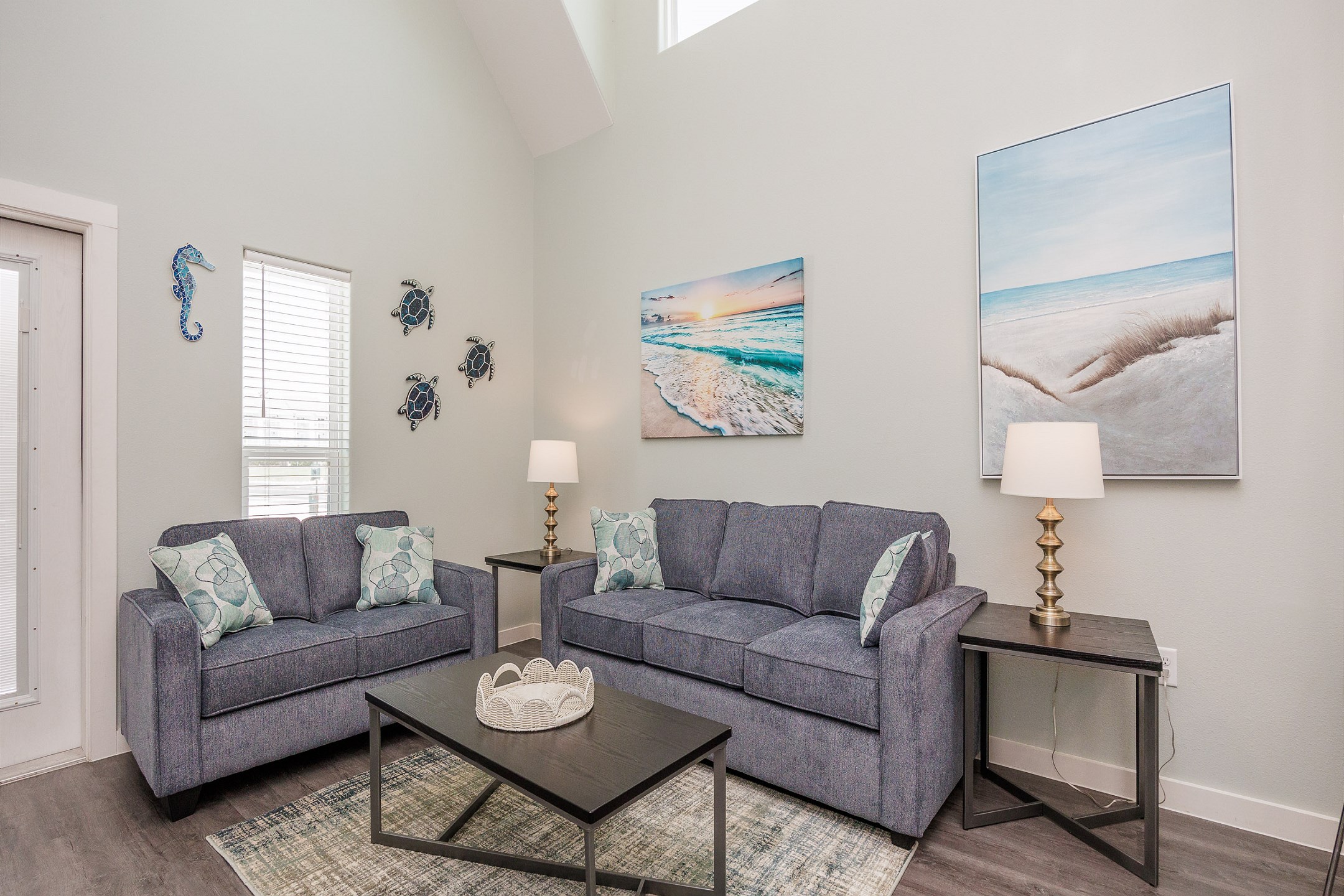 Living space with new and updated furniture, offering a sleeper sofa and love seat with coastal features throughout