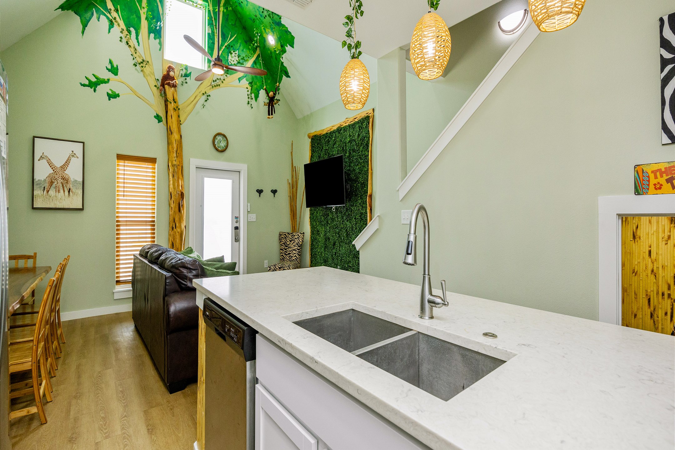 Bright, open-concept kitchen, dining, and living areas with a jungle theme