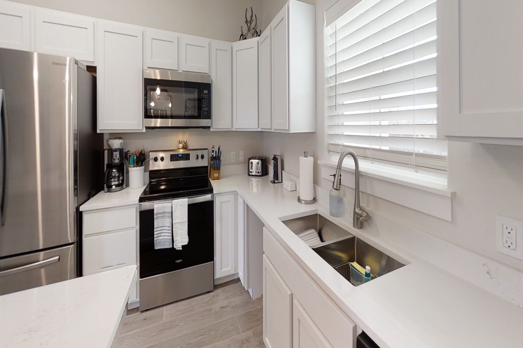 Fully stocked kitchen with barstools and coffee maker that opens up into the living / dining area 