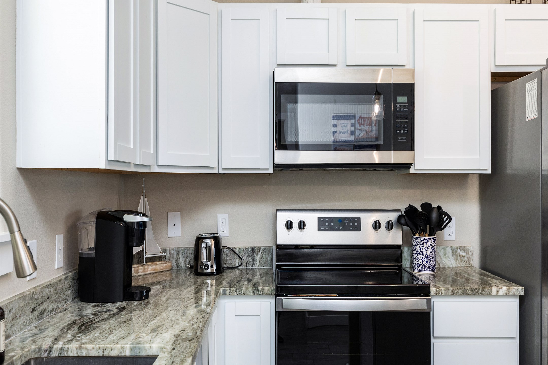 Fully equipped kitchen area with coffee maker, toaster, cookware, dinnerware, and other kitchen essentials provided