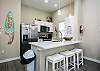 Bright dining area with modern appliances and three bar stools for entertaining 