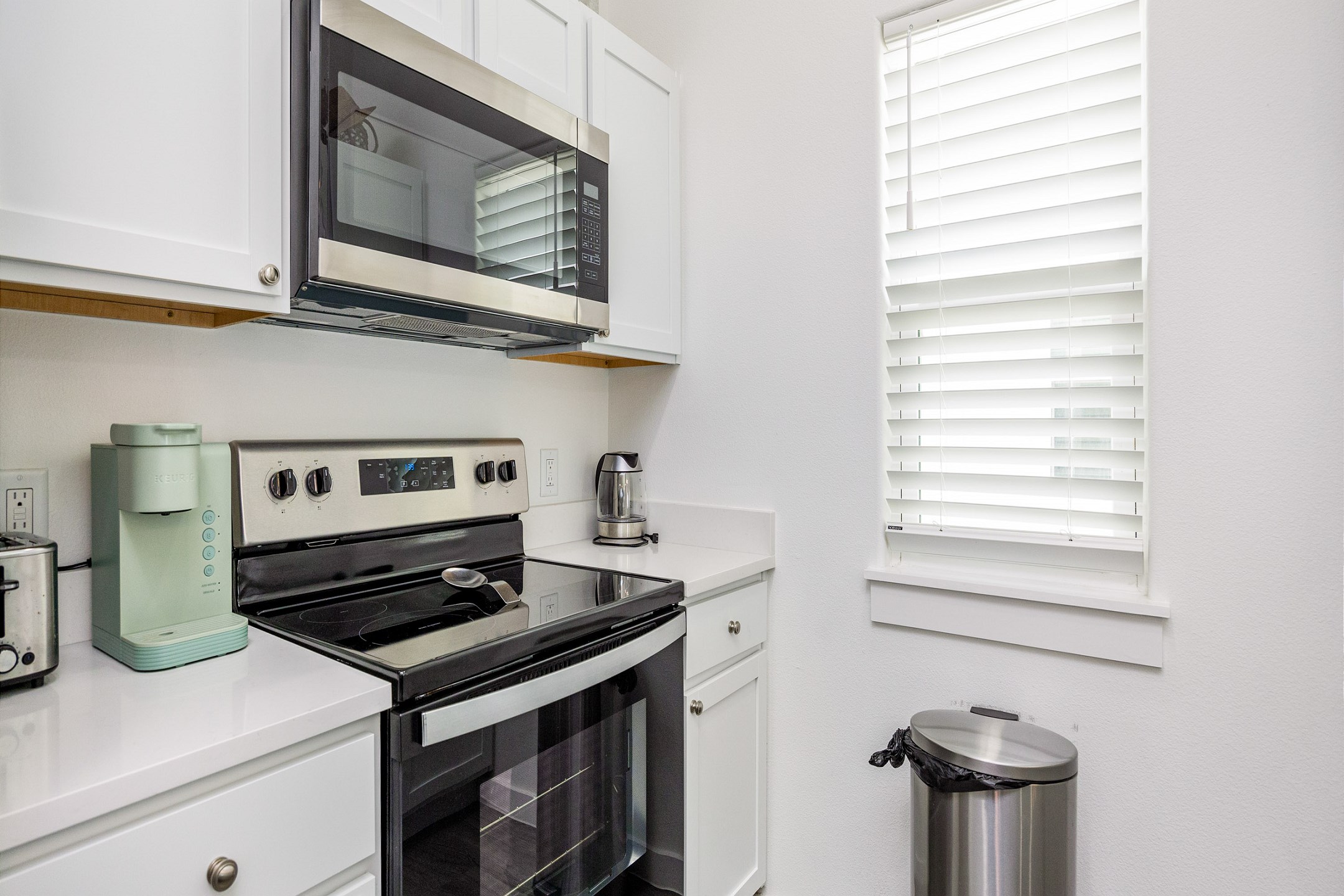 Fully equipped kitchen with coffee maker, toaster, cookware, dinnerware, and other kitchen essentials provided