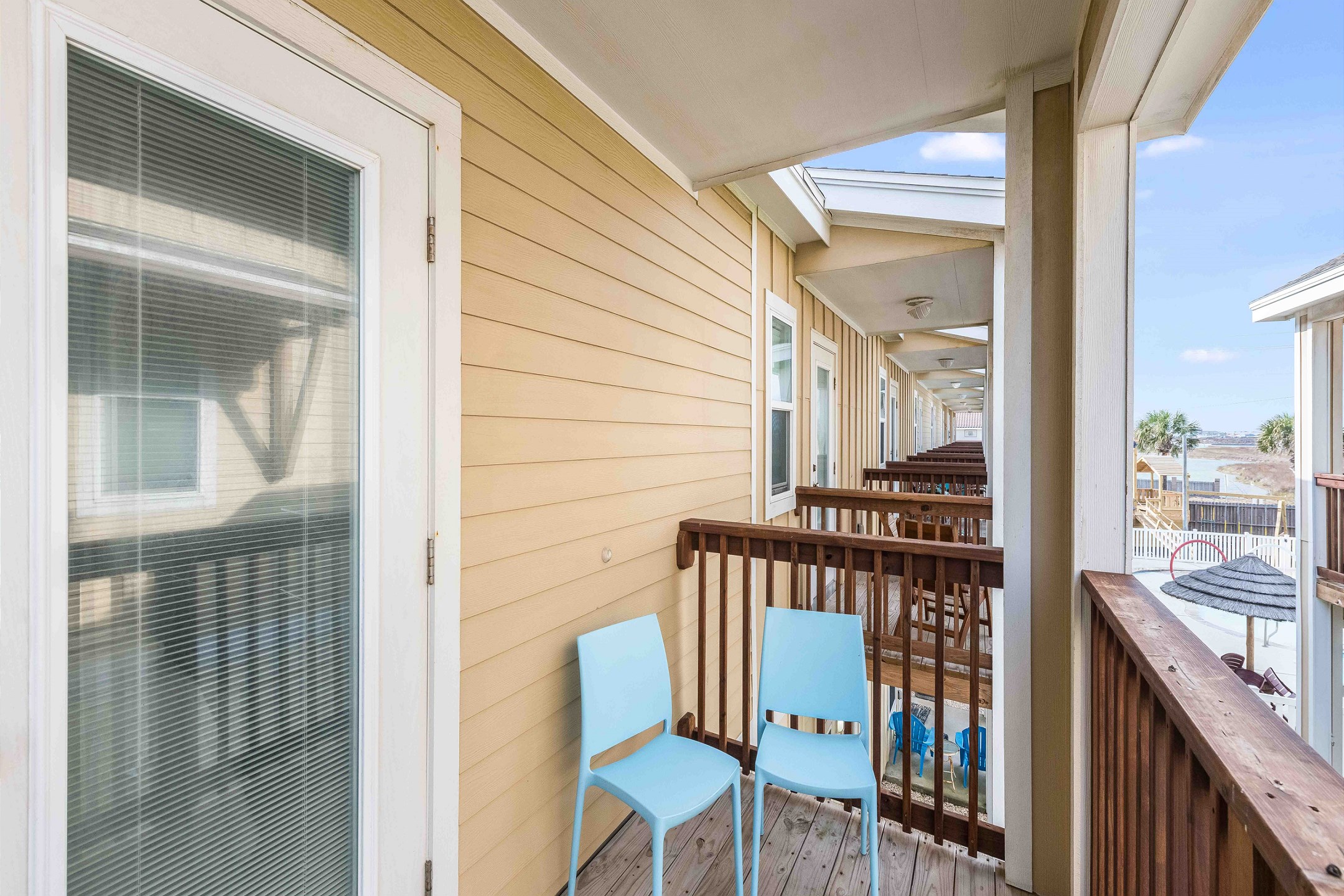 Private balcony off the master bedroom with chairs and partial views of the pool 