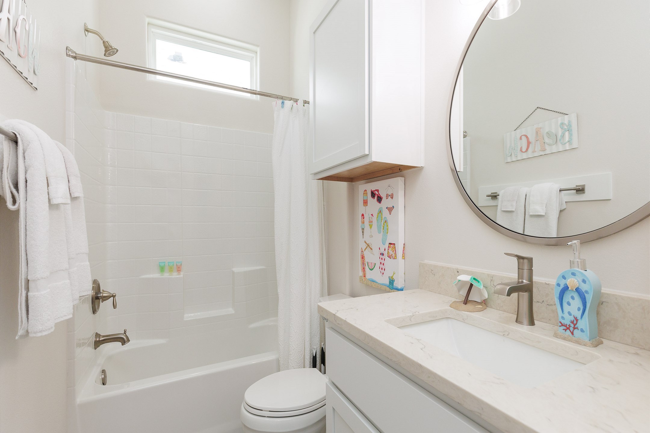 Guest bathroom off hallway with single sink, toilet, and tub/shower combo 