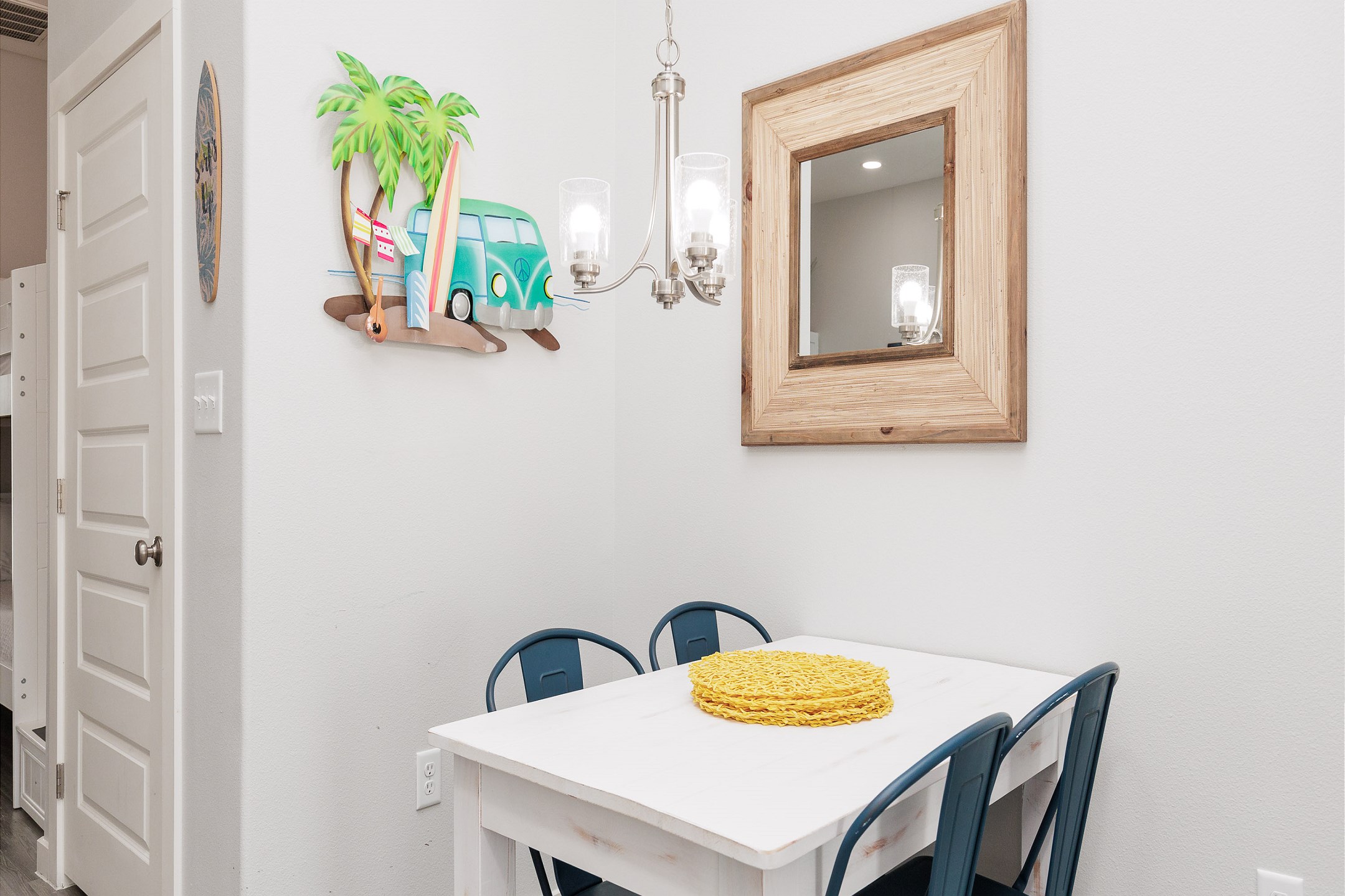 Quaint dining space for seating for four with beach-themed artwork