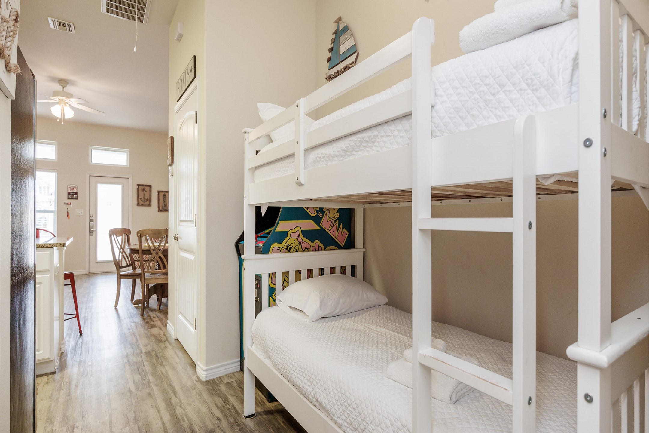 Twin of twin size bunk bed off the hallway with arcade game 