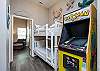 Twin over twin size bunk bed in the hallway, along with arcade game to play 