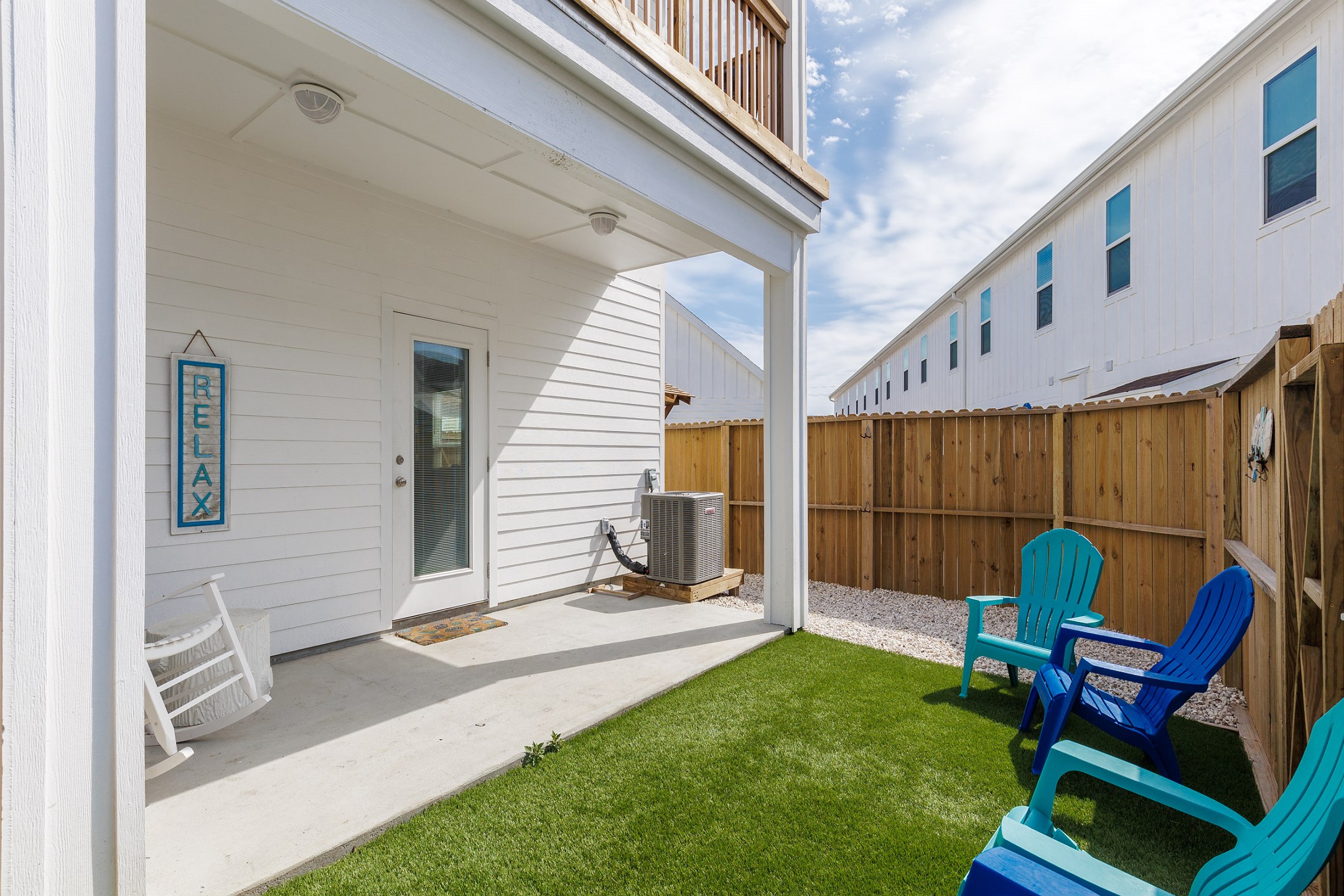 Private, fenced in patio with chairs and turf