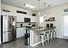 Modern kitchen island with stainless steel appliances and four bar stools 