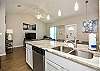 Bright kitchen area with beautiful modern light fixtures and plenty of counterspace 