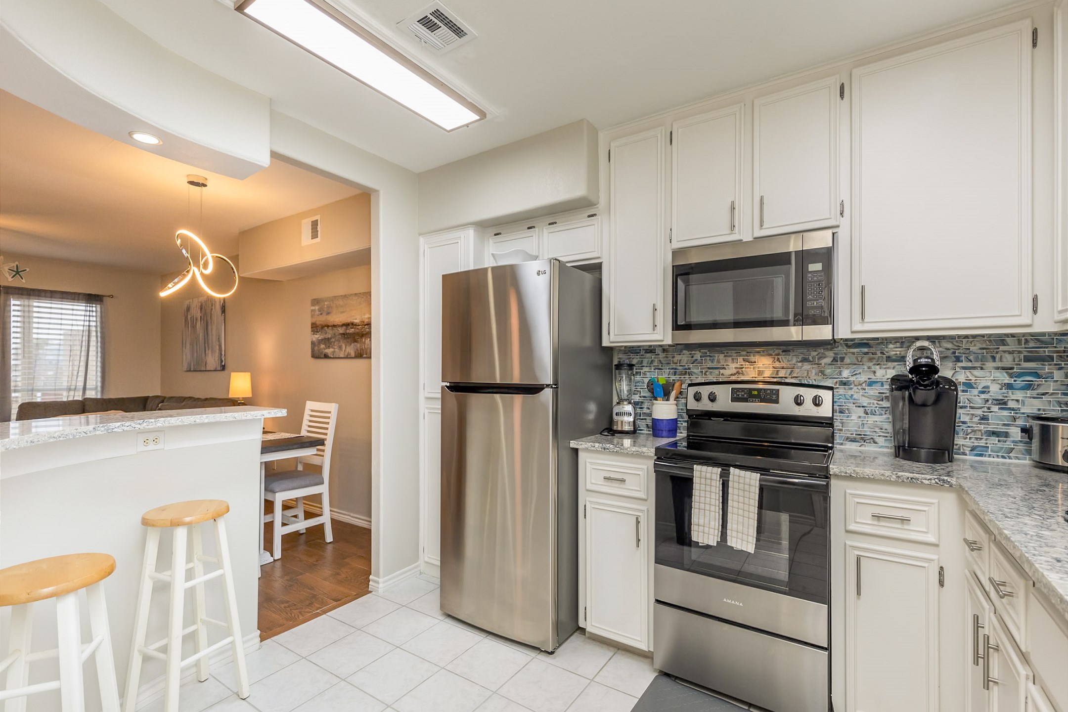 Fully equipped kitchen with stainless steel appliances offering an open concept into the dining and living areas 