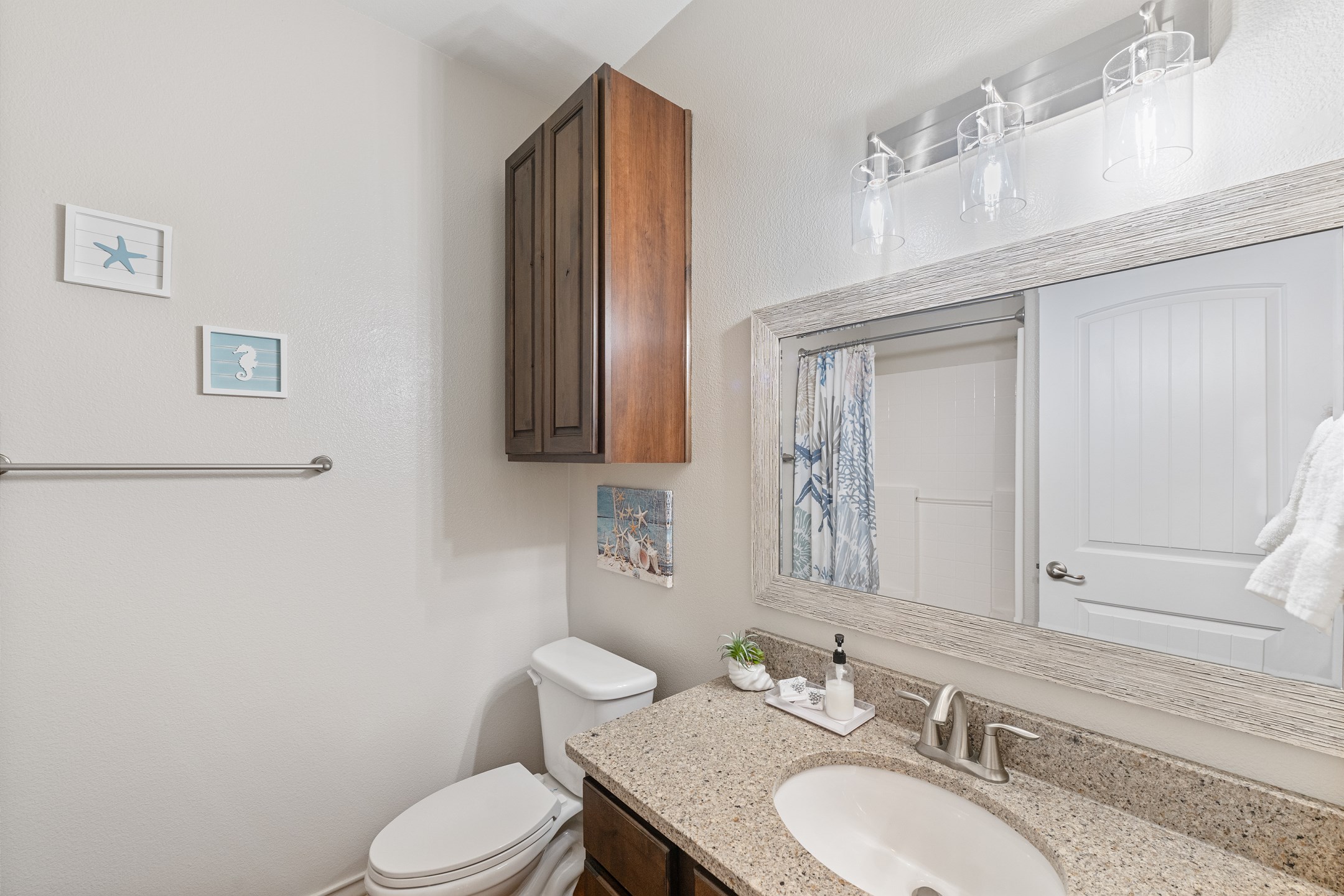 Guest bath has a walk-in shower, granite counters, and beachy decor