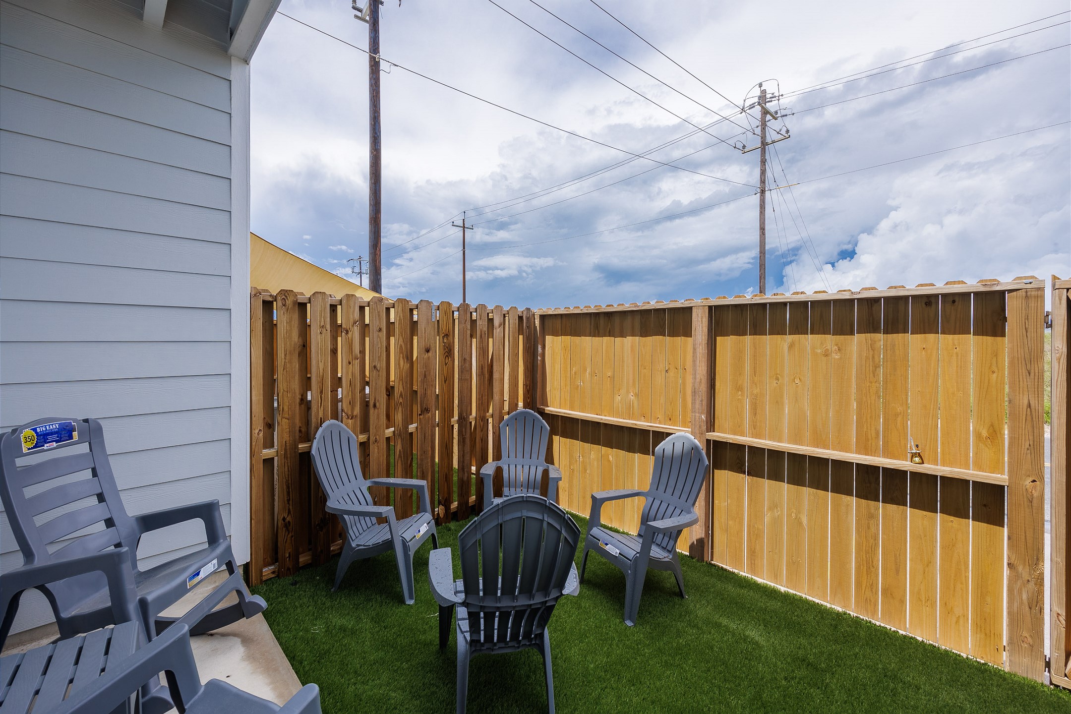 Private, fenced in patio off the master bedroom with chairs, turf grass, and access out the back gate 